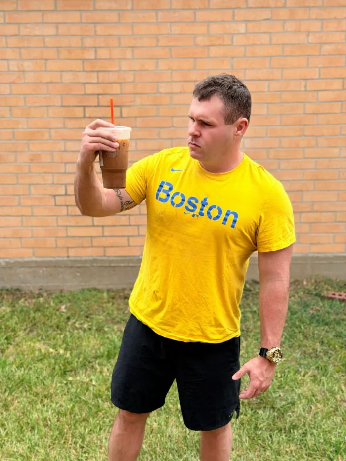 The same man holding the cup up and squinting at it